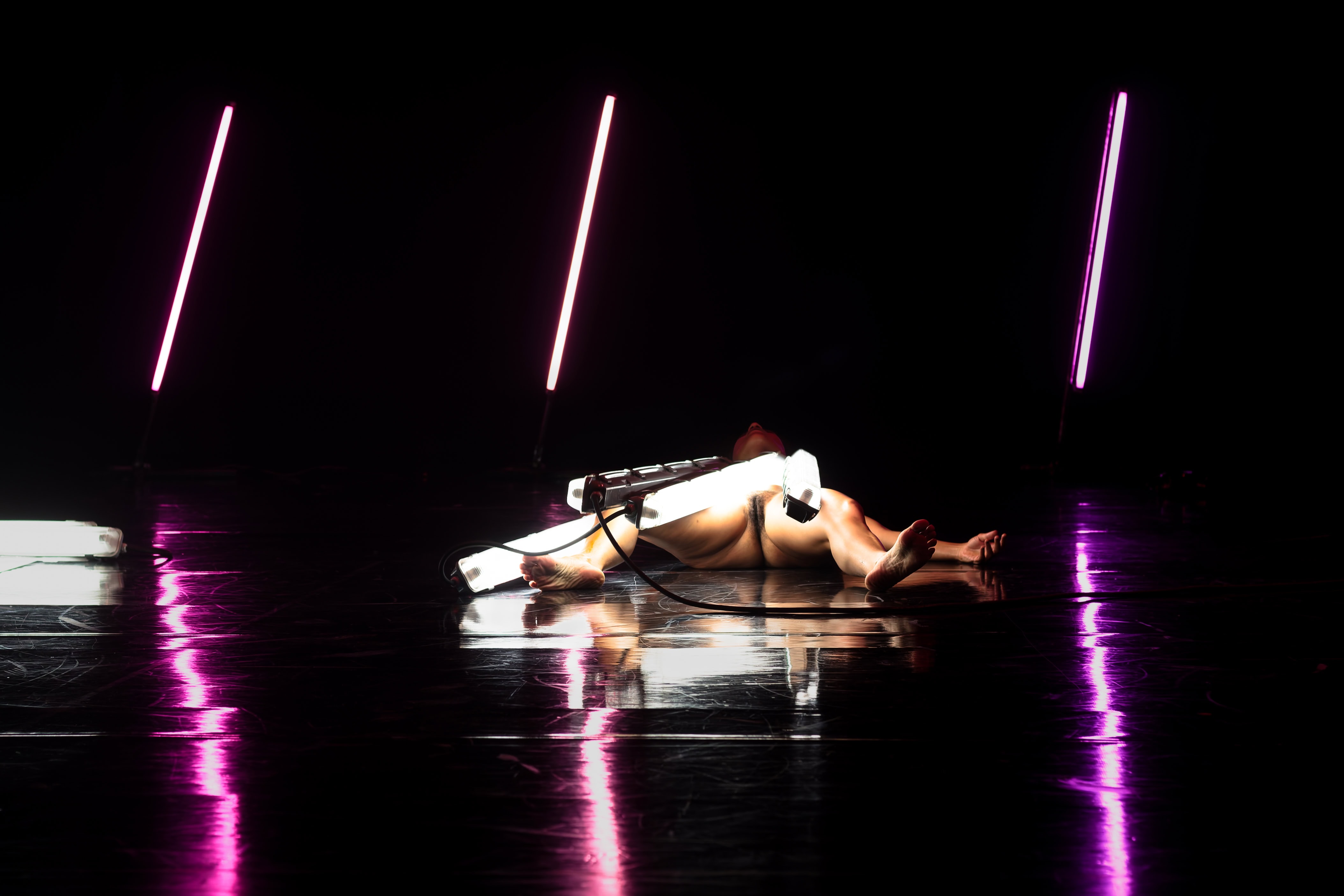Corps en mouvement avec lumières violettes, performance artistique.