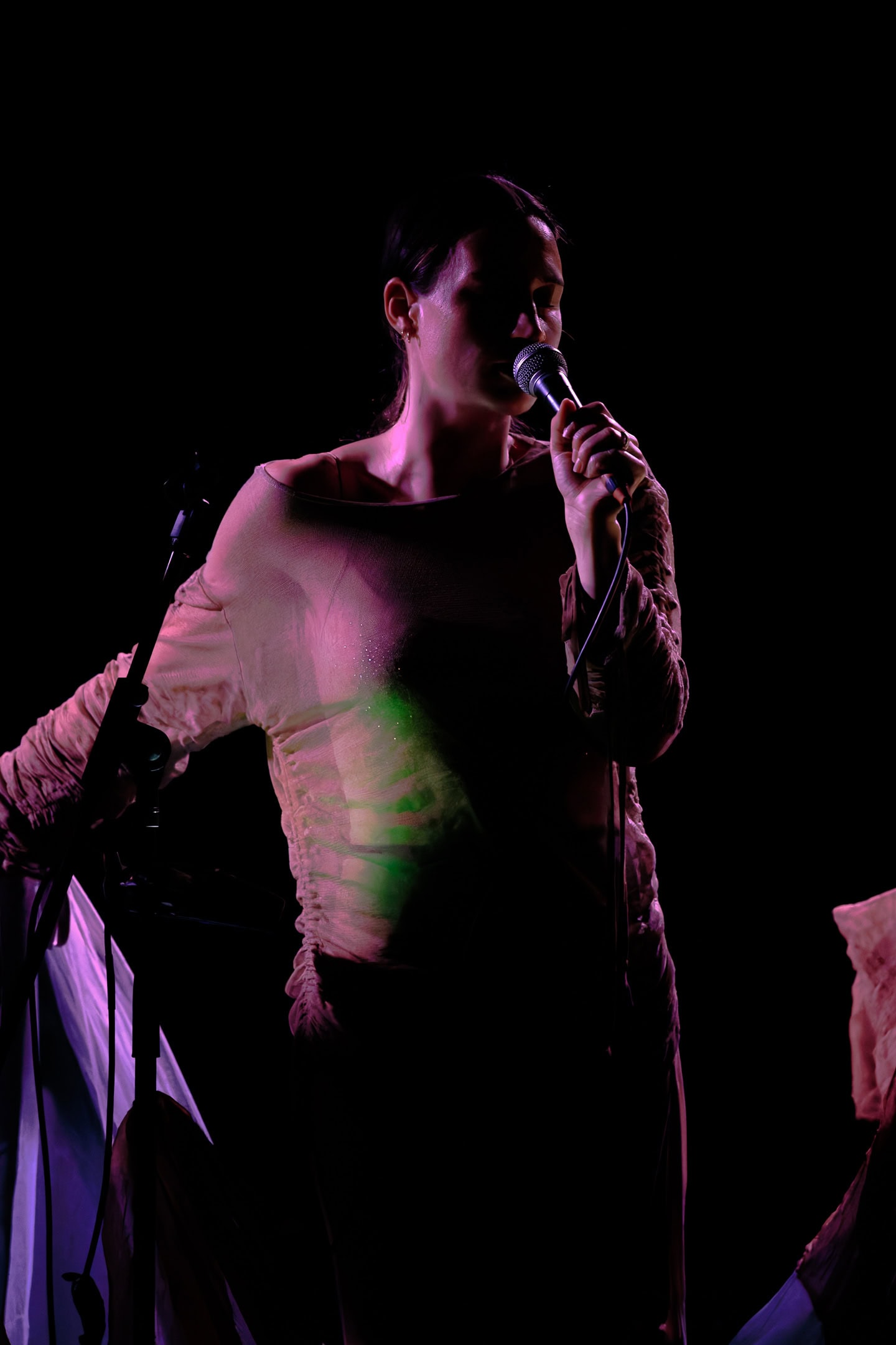 Dahan Jonathan en performance, chantant dans une ambiance sombre et mystérieuse.