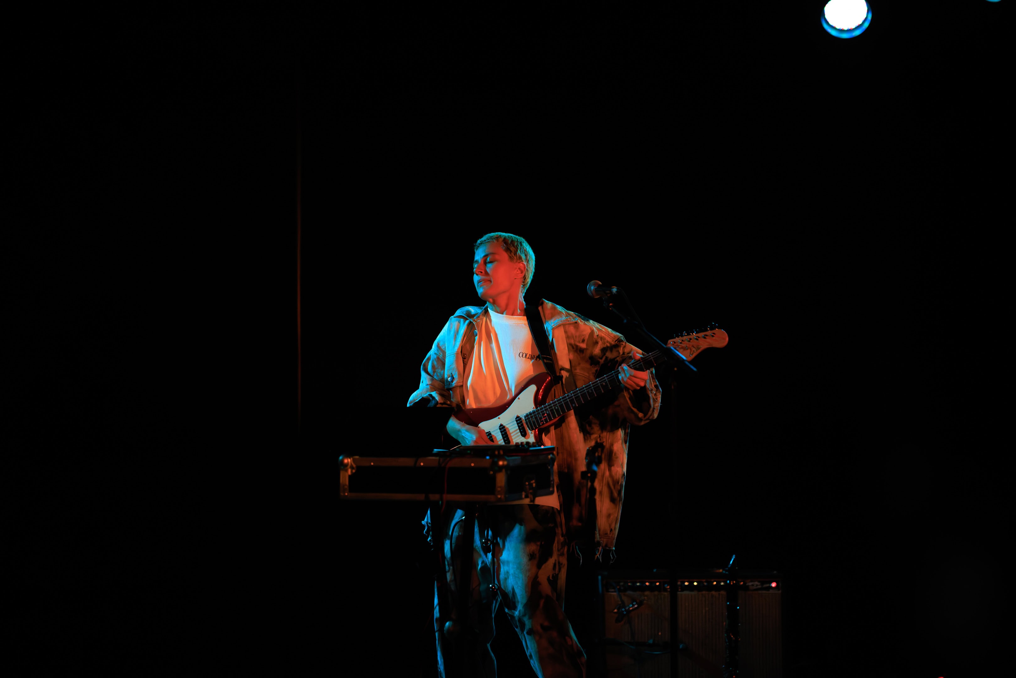 Musicien jouant de la guitare lors d’un concert en scène sombre.